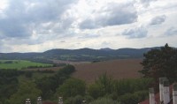 Pohled z věže k západu: Lužické hory - nejvyšší viditelný kopec je Hvozd (Hochwald) - 749 m. n. m.; i na tomto snímku viditelná věžovitá stavba (rozhledna) je již na německém území. V dávné minulosti bylo i území na sever od Hvozdu - Záhvozd - součás
