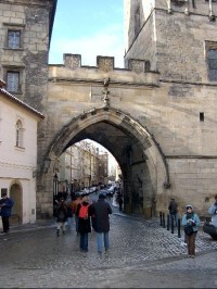 Brána: Branou mezi oběma mosteckými věžemi se vchází na Malou Stranu. Brána má nadezdívku s cimbuřím, je opatřená znaky zemí Václava IV.( lev lucemburský, lev český a moravská orlice, pod nimi znak Starého Města na straně mostní, vratislavská orlice,